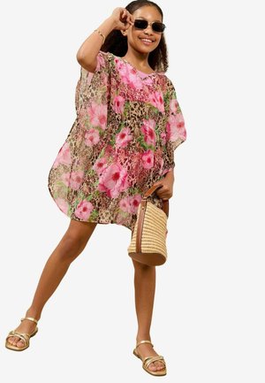 Transparenter, leichter Überwurf mit einem Blumen- und Tiermuster in Rosa und Beige. Kombiniert mit goldenen Sandalen und einer geflochtenen Tasche.