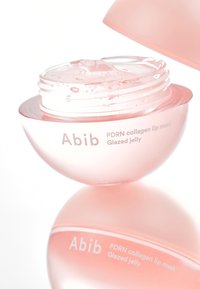 Contenant rond et translucide de couleur rose avec un couvercle, présentant une surface brillante. L'étiquette indique "Abib PDRN collagen lip mask Glazed jelly".