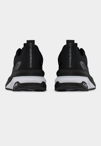 Ζευγάρι μαύρα και λευκά sneakers EA7 Emporio Armani, ορατά από πίσω, με το όνομα της μάρκας στην ετικέτα της φτέρνας και στη σόλα.