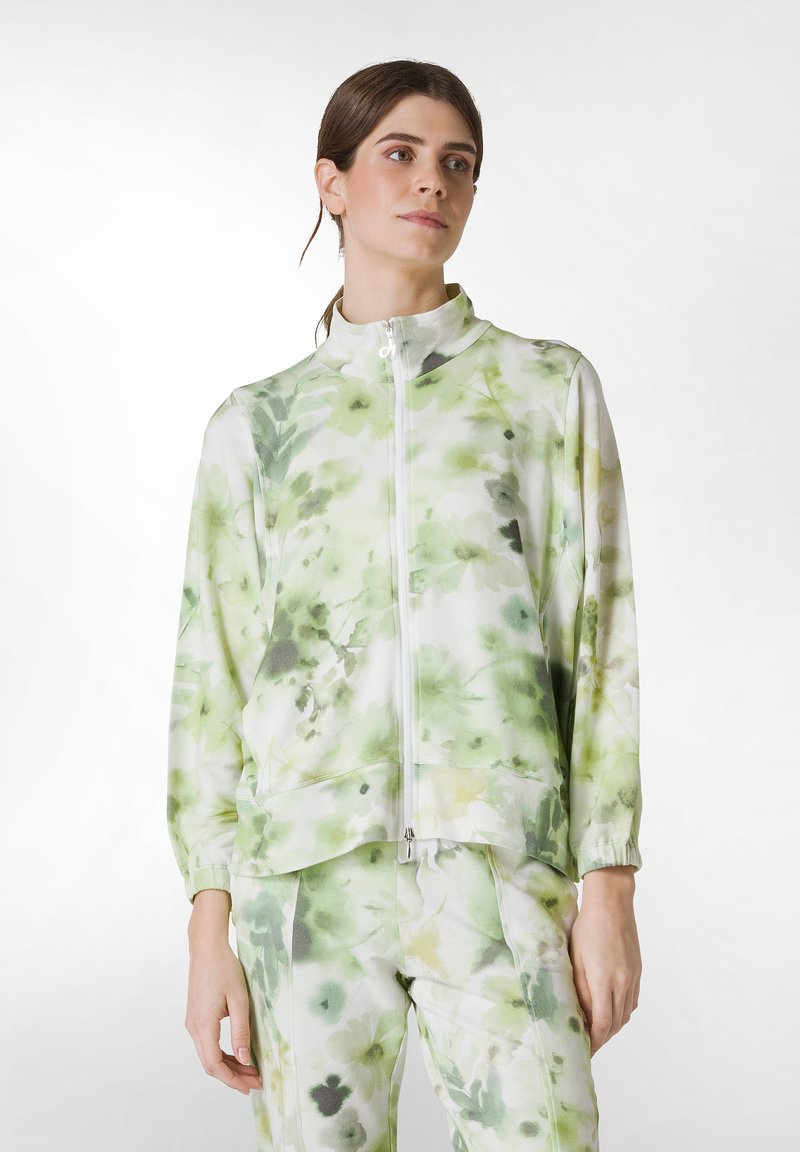 Letvægts zip-up jakke i blødt stof, med et grønt blomster mønster, høj krave og elastiske ærmer, parret med matchende bukser.