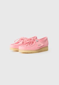 Pantofi din suede roz cu design cu sireturi, vârf rotund și cusături texturate. Prezintă o talpă din cauciuc de culoare deschisă și detaliu cu logo din metal.