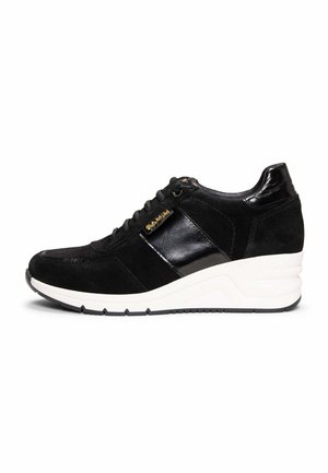 Zapatilla deportiva de cuña negra con detalles en ante y cuero brillante, cordones negros, etiqueta de marca dorada y suela blanca gruesa.