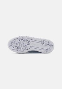 White rubber sneaker sole with circular patterns, textured grip, and an embossed logo. Light gray accents with smooth edges and distinctive tread design.