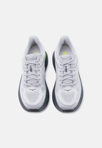 Ζευγάρι αθλητικών παπουτσιών τρεξίματος ανοιχτού γκρι με επάνω μέρος από δίχτυ, μαύρες ενδιάμεσες σόλες και φωτεινά κίτρινα σημεία, που φαίνονται από πάνω σε λευκό φόντο.