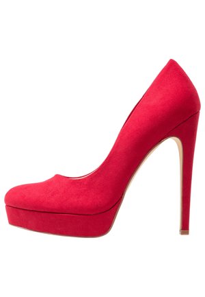 Escarpin à plateforme en daim rouge avec bout fermé arrondi et talon stiletto fin sur fond blanc.