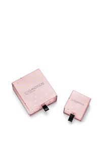 Rozā iepakojums ar zelta sirds rakstiem, ar atvilkšanas cilni atvēršanai. Ietver lielāku kastīti un mazāku kastīti, abām ir zīmola identifikācija.