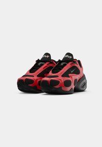 Zapatillas deportivas rojas y negras con parte superior texturizada, paneles de malla y amortiguación de aire visible en la suela. Presenta un diseño de cordones negros y un logo.