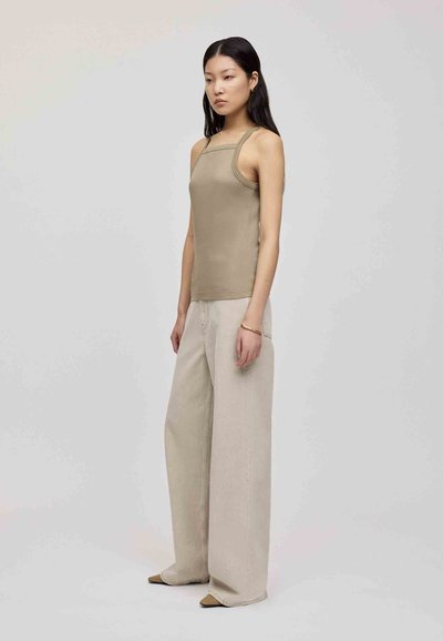 Beige fitted tank top with thin straps paired with wide-legged, light beige trousers. The outfit features a minimalist design and soft texture.