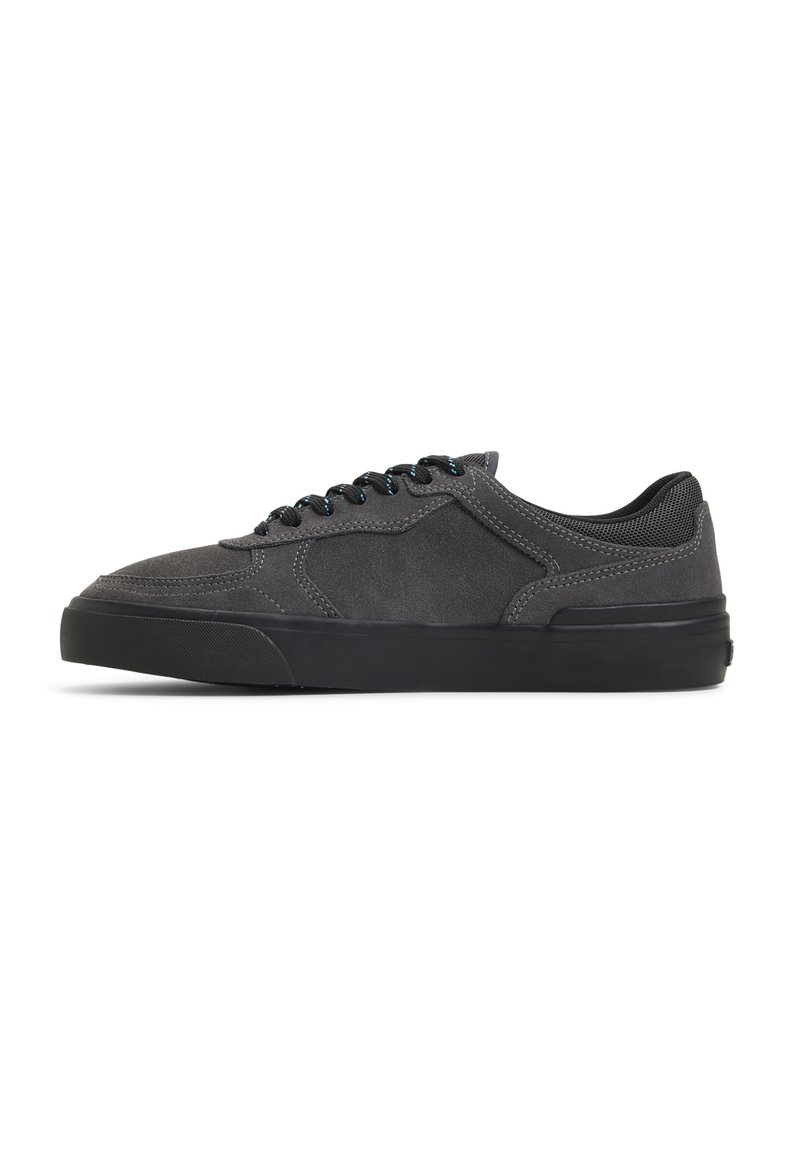 Gray suede sneaker with black rubber sole, rounded toe, and contrasting blue laces. Features a low-top design and padded collar for comfort.