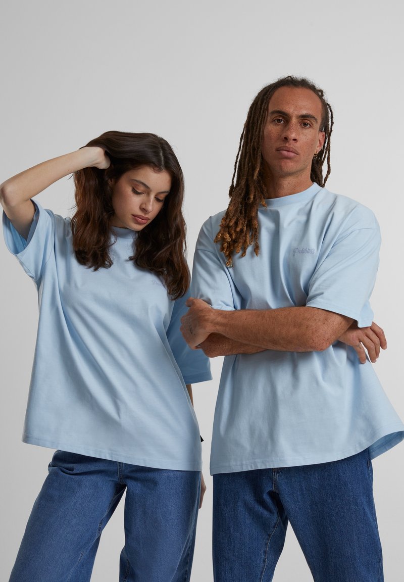 Camisetas de algodón azul claro con mangas cortas, corte relajado y cuello redondo. El diseño presenta un sutil logotipo en el pecho.