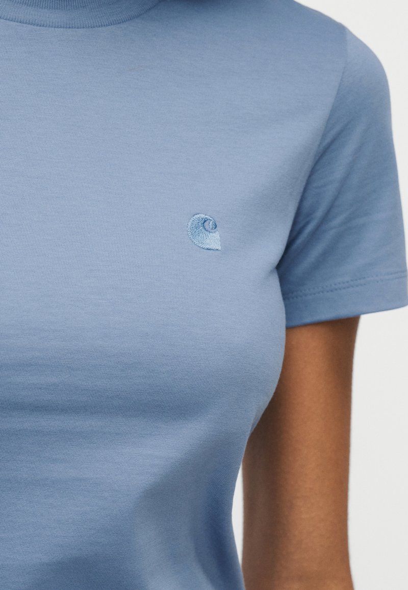 Hellblaues kurzärmeliges T-Shirt mit kleinem, eingesticktem Wirbel-Logo auf der linken Brust, getragen von einer Person mit mittlerem Hautton.