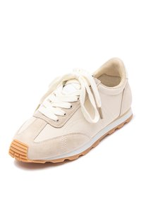 Sneaker beige realizzata in suede e tessuto, con punta arrotondata, lacci piatti e suola in gomma con texture a righe. Design minimalista.