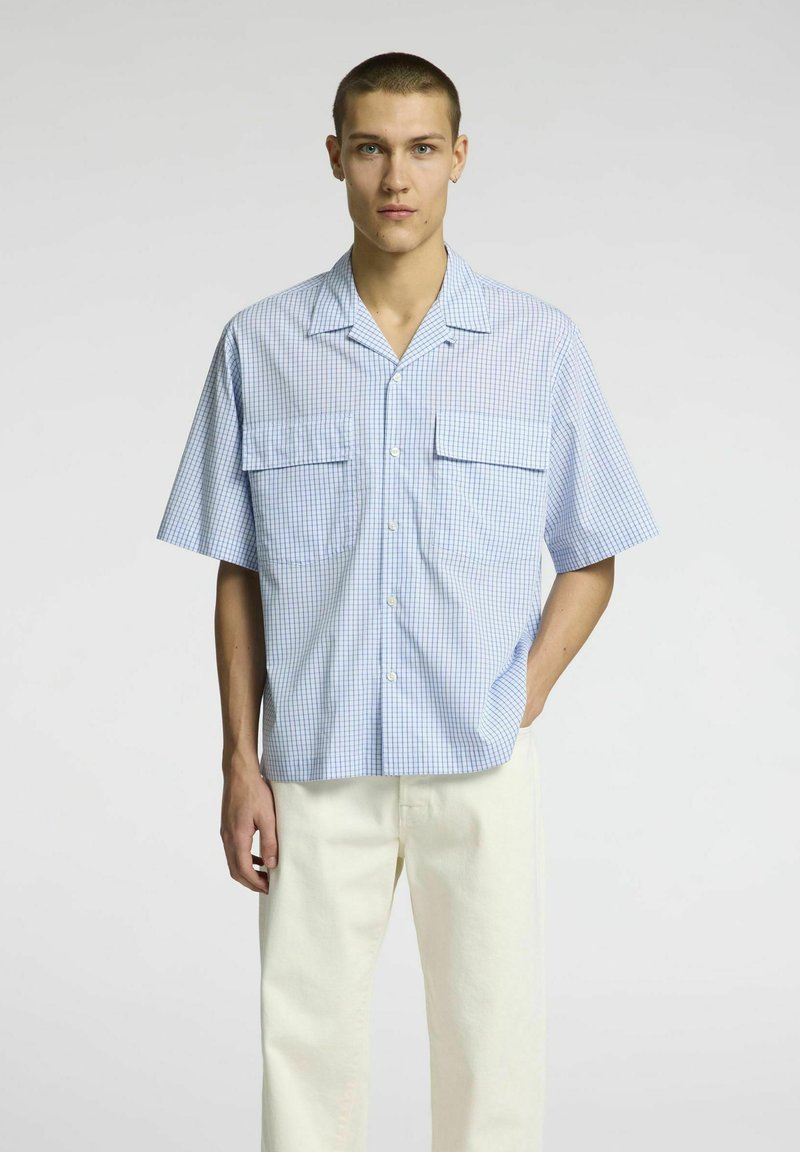 Šviesiai mėlynos ir baltos languotos trumpų rankovių marškiniai su mygtukais, pasižymintys dviem priekinėmis kišenėmis, laisvu siluetu ir stovyklos apykakle.