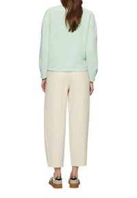 Licht mintgekleurde sweatshirt met een relaxte pasvorm, gecombineerd met crèmekleurige wijde broeken. Het schoeisel heeft een gestructureerde bruine zool en metallic accenten.