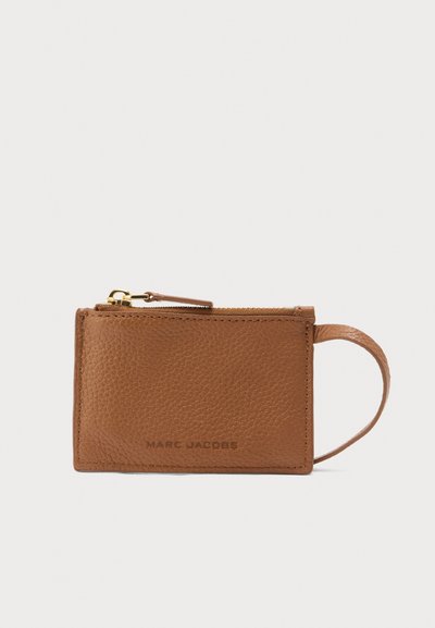 Καφέ δερμάτινη θήκη καρτών με κλείσιμο με φερμουάρ, που διαθέτει λεία υφή και λουράκι. Στην πρόσοψη υπάρχει τυπωμένο το λογότυπο Marc Jacobs.