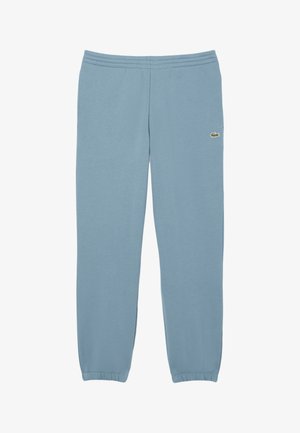 Joggers de algodón azul claro con cintura elástica, puños ajustados y un pequeño logo verde en la pierna izquierda. Textura suave.