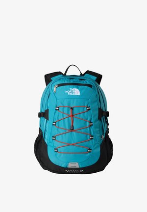 Mochila verde azulado y negra con un compartimento principal, bolsillo exterior con cremallera y sistema de cuerdas elásticas naranjas. Cuenta con correas acolchadas y bolsillos de malla.
