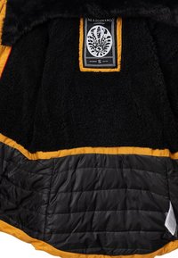 Black fleece interior jacket with yellow trim, featuring a quilted black lining. Includes a label with intricate design details.