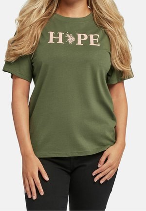 Kobieta w oliwkowo-zielonej koszulce z napisem "HOPE" dużymi literami i małą grafiką przedstawiającą konia i jeźdźca zamiast litery O.