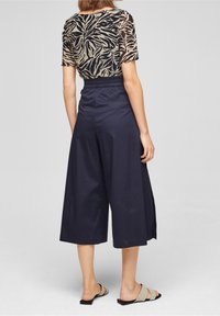 Top de manga corta con estampado de animal en negro y beige, combinado con culottes azul marino que cuentan con una cintura elástica y piernas anchas.