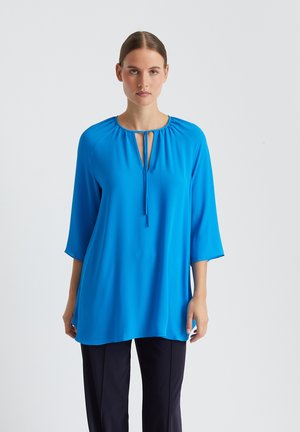 Lichtblauw, losvallend blouse met driekwartmouwen, een ronde halslijn en een keyhole-opening met een strikdetail aan de voorkant.