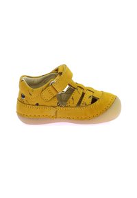 Sandalia de cuero amarilla con cinta Velcro, diseño abierto, acentos de costura y suela de goma color beige claro. Presenta pequeños patrones negros en el interior.