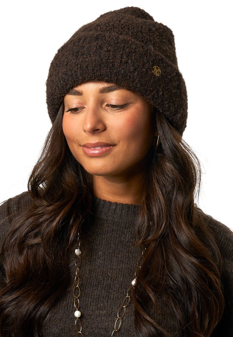 Brązowa dziana czapka z grubym, teksturowanym splotem i lekko podwiniętym brzegiem. Posiada małe złote logo z boku.