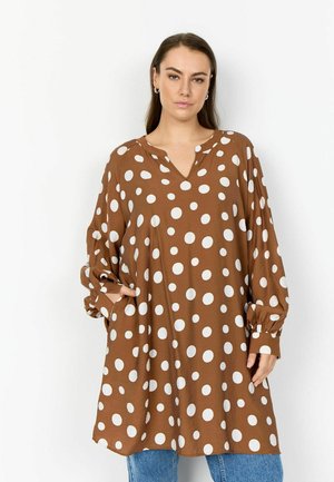Hnedá tunika s bielymi bodkami, výstrihom do V, dlhými rukávmi a elastickými manžetami. Vyrobená z ľahkej látky, s bočnými vreckami.