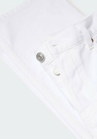 Gros plan sur un jean en denim blanc plié montrant une fermeture par bouton métallique, une boucle de ceinture et des détails de couture sur la poche.