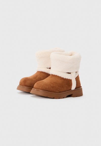 Bottes d'hiver en daim marron avec une épaisse doublure en fourrure crème repliée sur le dessus et des semelles en caoutchouc robustes.