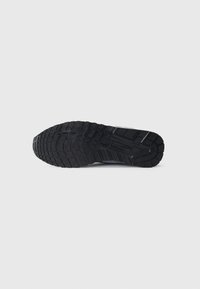 Black rubber shoe sole featuring a textured tread pattern, designed for traction, with defined grooves and a solid construction.