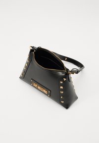 Black leather handbag with gold-tone studs, zipper closure, and a branded plaque. Features a structured shape and a detachable strap.