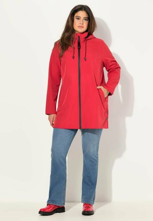 Red waterproof jacket with a hood, front zipper, and side pockets. Worn with blue jeans and red boots. Smooth fabric texture.
