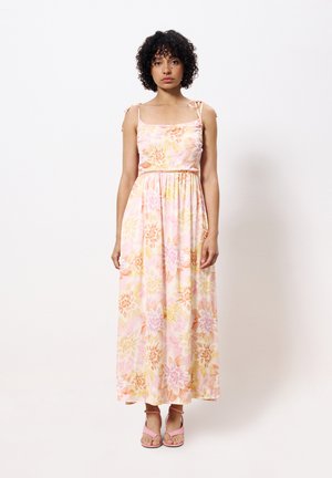 Floral maxi dress in shades of pink and yellow, with thin straps and a cinched waist. Complemented by pink strappy sandals.