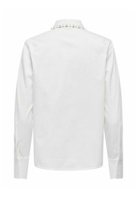 Chemise blanche à manches longues avec un ourlet droit et des poignets boutonnés, ornée d'une rangée décorative de petites perles le long du col.