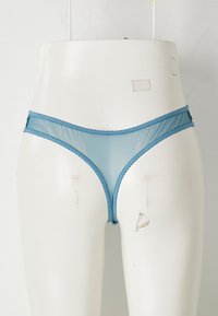 Lichtblauwe gaas-string met scalloped randen. Heeft een minimalistisch ontwerp, doorschijnende textuur en elastische banden rond de taille en aan de zijkanten.