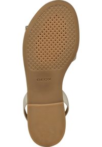 Suela de goma beige con superficie texturada y agujeros de ventilación; cuenta con un borde liso y el logo "GEOX" grabado.