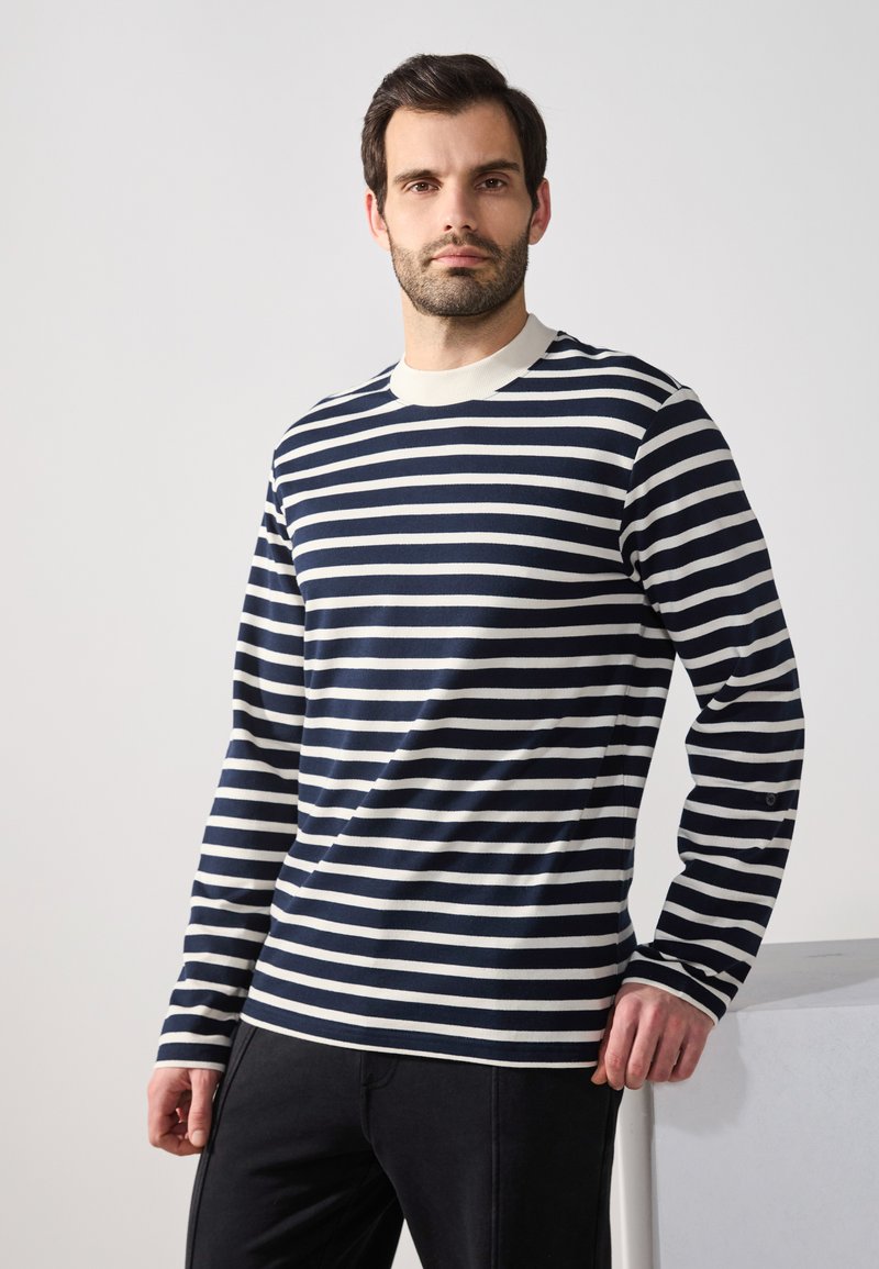 Marineblau-weiß gestreiftes Langarmshirt mit Rundhalsausschnitt; weicher Stoff; mit kontrastierendem Rippkragen und enganliegenden Bündchen.