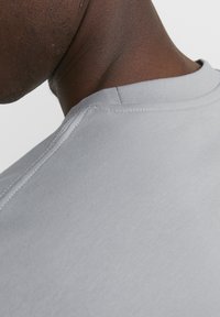 Light gray t-shirt collar with a ribbed texture, showcasing clean stitching and a soft fabric surface. A close-up view emphasizes the neckline.
