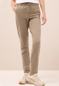 Ljust beige joggerbyxor med elastisk midja och justerbar dragsko. Slät tyg, figurnära vid vristen, med sidofickor.