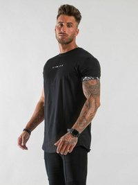 Svart t-shirt med kort ärm och vit text "LIMITED" på bröstet, samt mönstrade manchetter, matchad med åtsittande svarta byxor.