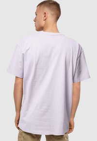 Lavendel bomulds t-shirt med korte ærmer, rund hals og afslappet pasform, set bagfra, med minimal tekstur og ingen mønstre.