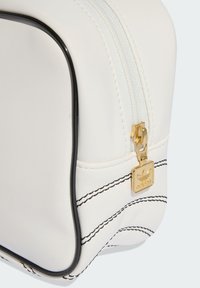 White synthetic cosmetic bag with black accents, gold zipper hardware, and visible stitching details. Smooth texture with rounded edges.