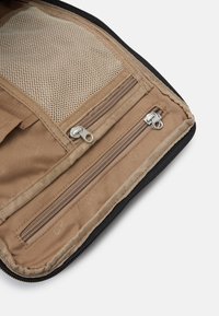 Organizador de tecido bege com um bolso em malha e dois compartimentos com fecho. Bordas acabadas com um acabamento preto. Tecido interior texturizado.