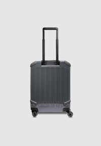 Valise à roulettes gris foncé avec une surface texturée à nervures, deux roues noires et une poignée rétractable. Le bagage est équipé de coins renforcés.