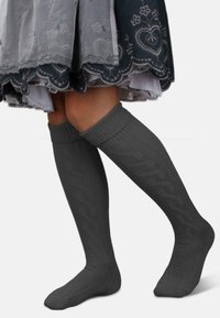 Graue kniehohe Socken mit einem strukturierten Zopfmuster und gerippten Bündchen, die zu einem grauen Rock mit Spitzenbesatz passen.
