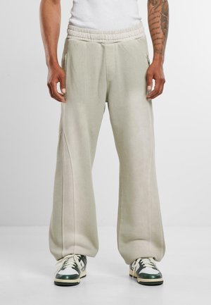 Lys grå, oversized sweatpants lavet af blødt stof. Har en elastisk talje og sidelommer. Bæres med grønne og hvide sneakers.