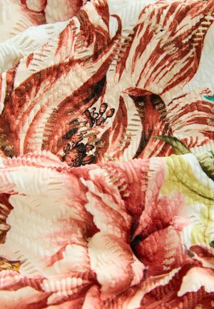 Gėlių raštų audinys raudonos ir grietinėlės spalvų atspalviuose, turintis tekstūrinių elementų ir įmantriai detalių, tinkantis apmušalams ar dekorui.