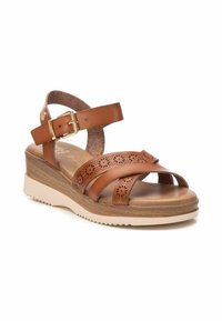 Sandalo in pelle marrone con plantare in sughero texturizzato, fasce incrociate con motivi floreali intagliati e suola in legno chiaro a zeppa.