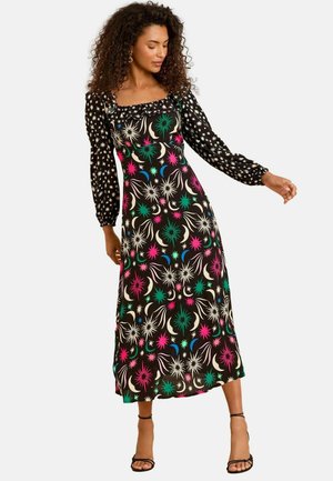 Abito maxi nero con corpetto aderente a pois bianchi, maniche lunghe e gonna con un motivo floreale multicolore.